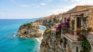 Vista panoramica di Tropea, con le sue case arroccate sulla scogliera a picco sul mare cristallino, e un balcone di una casa vacanze in primo piano.